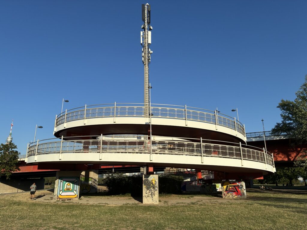 Urban pedestrian overpass with telecommunications tower under a clear blue sky